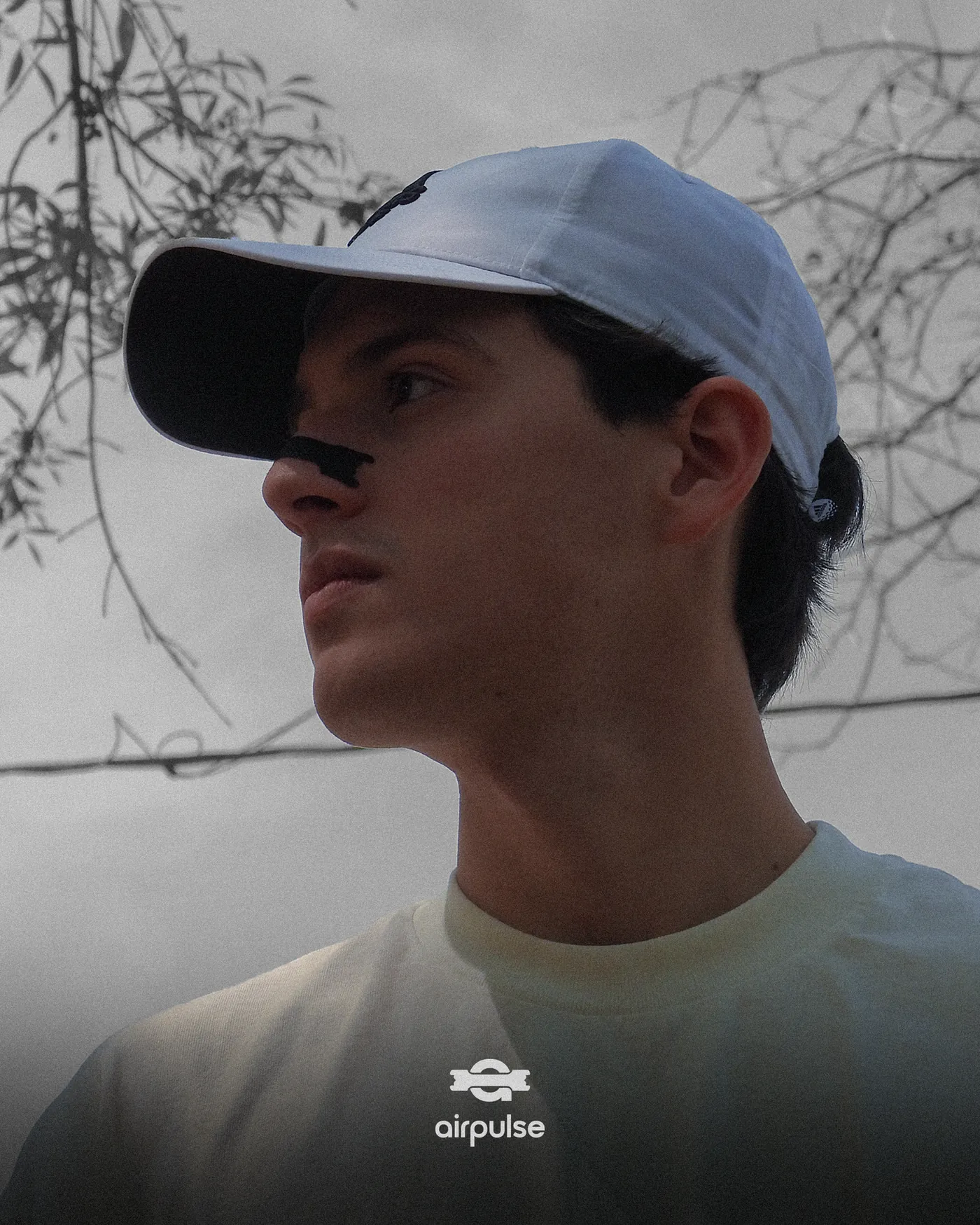 Retrato en blanco y negro de un hombre con gorra y una tira nasal Airpulse puesta